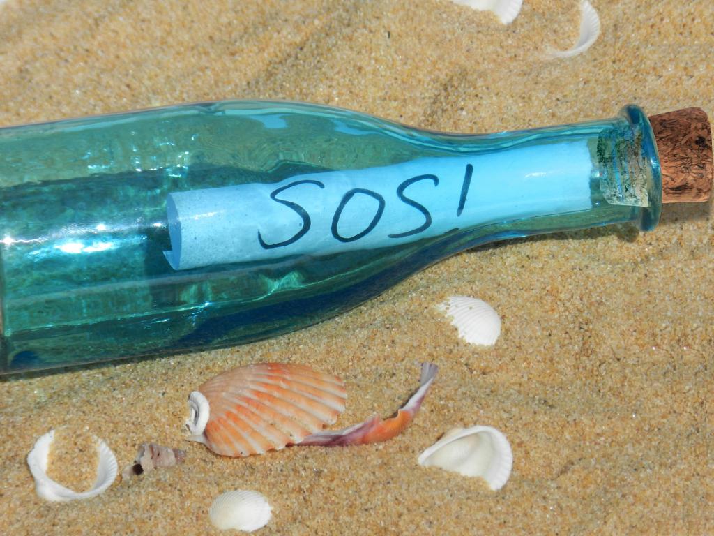 Mensaje escrito en una botella en una playa de arena.