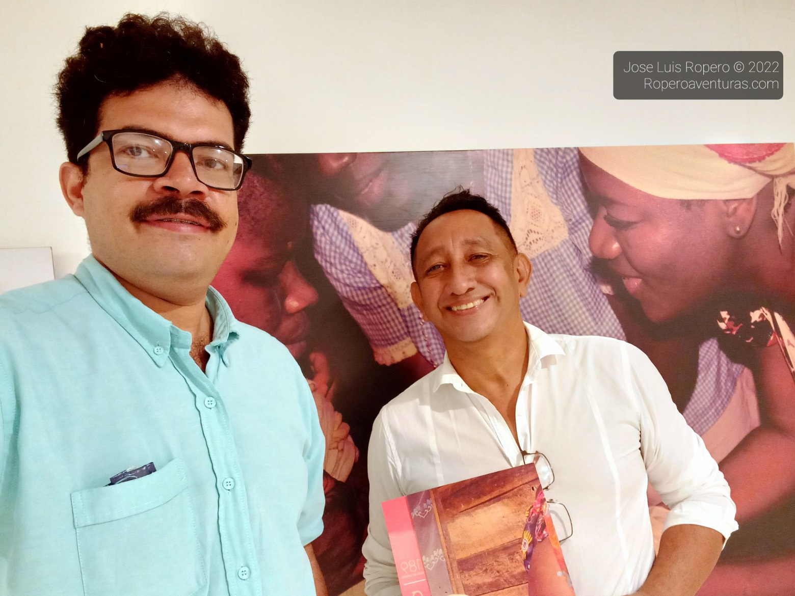 Selfie de dos hombres con una fotografía en segundo plano