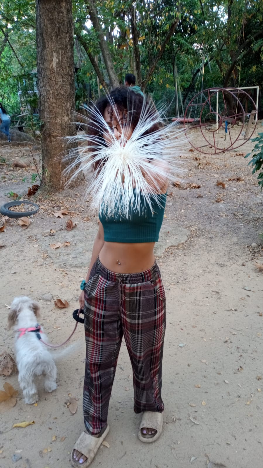 Una mujer sostiene una flor y un perro en la otra mano.