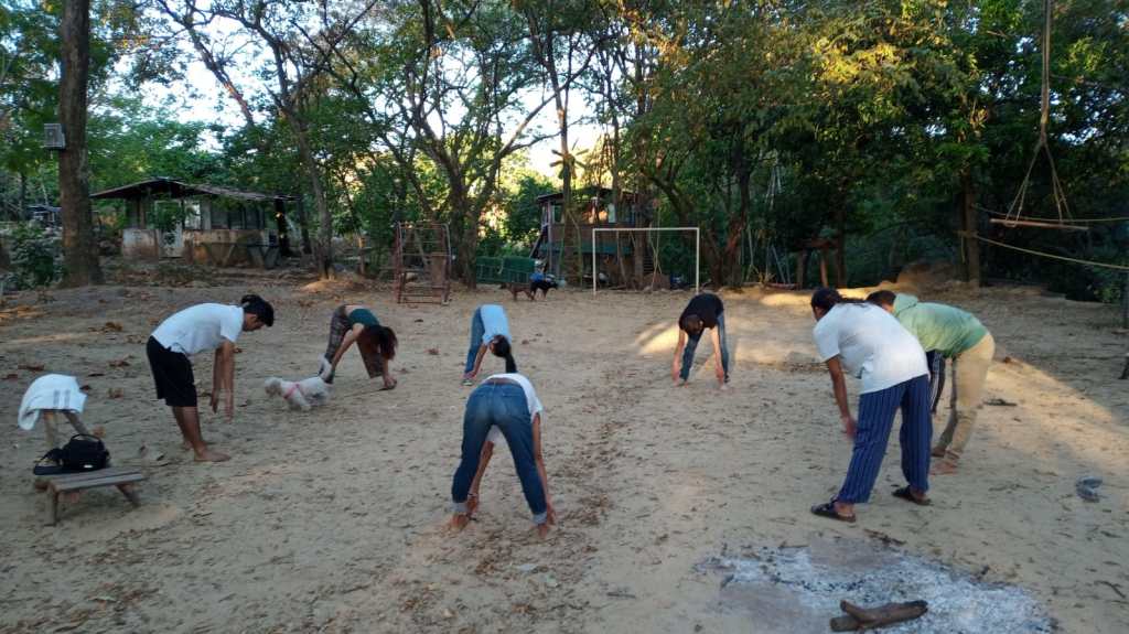 Grupo de personas hacen un calentamiento de yoga.