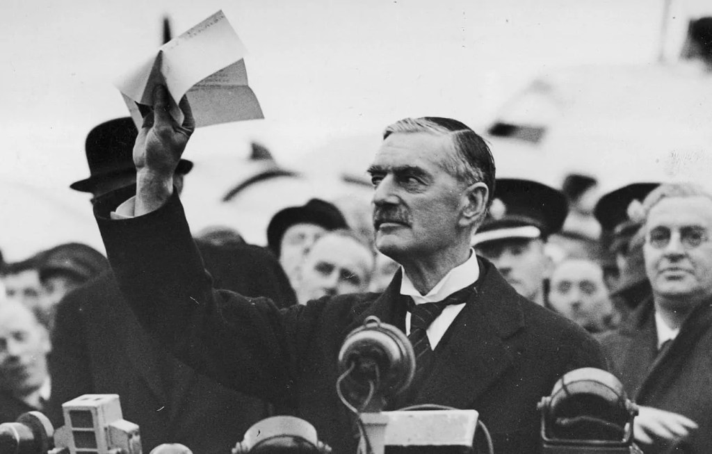 Primer ministro Británico Neville Chamberlain mostrando el infame acuerdo con Hitler